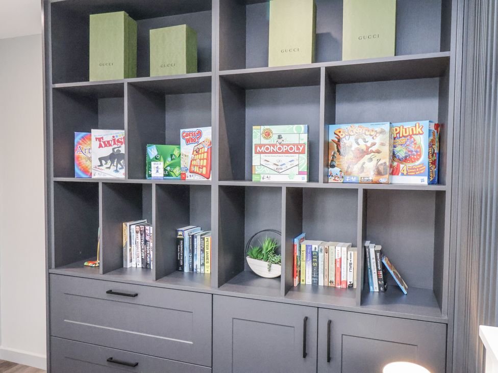 A living room with shelves containing games and books at Pearl Stone House in Whitby