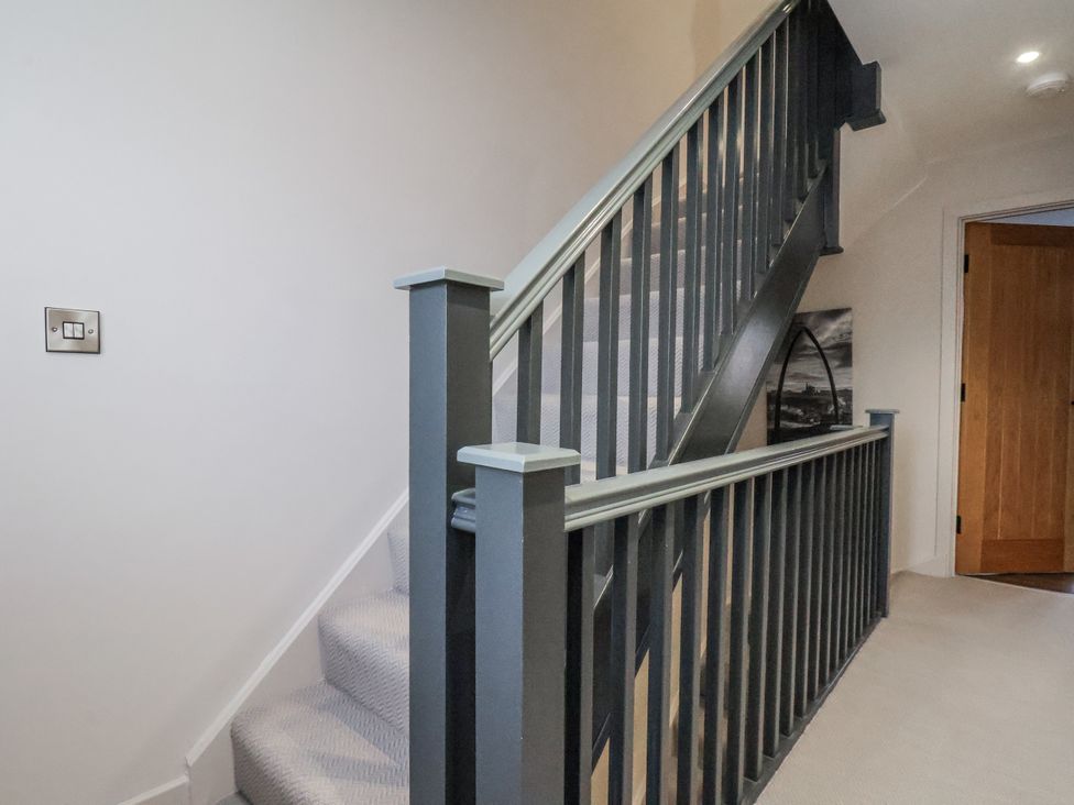 A staircase with a handrail and light switch at Pearl Stone House in Whitby