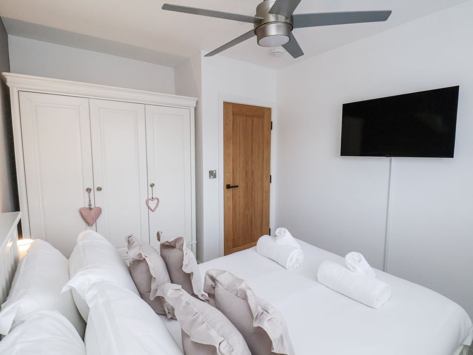 A bedroom with a bed, wardrobe and television at Pearl Stone House in Whitby
