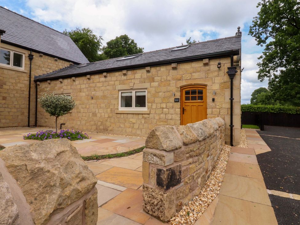 An exterior view of a house with a stone wall and paved pathway at Heron View