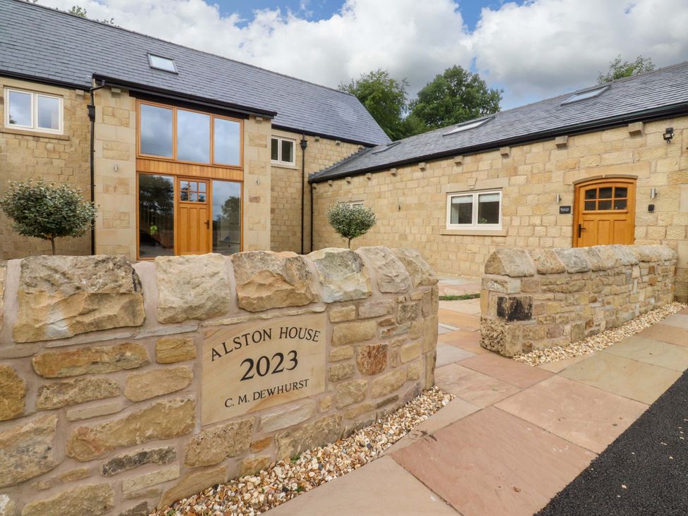 An exterior view of Alston House with stone wall and front entrance at Heron View 
