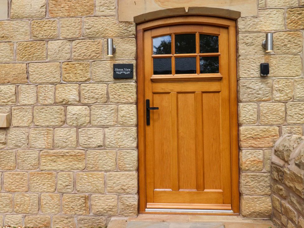 An entrance with a wooden door and stone wall at Heron View
