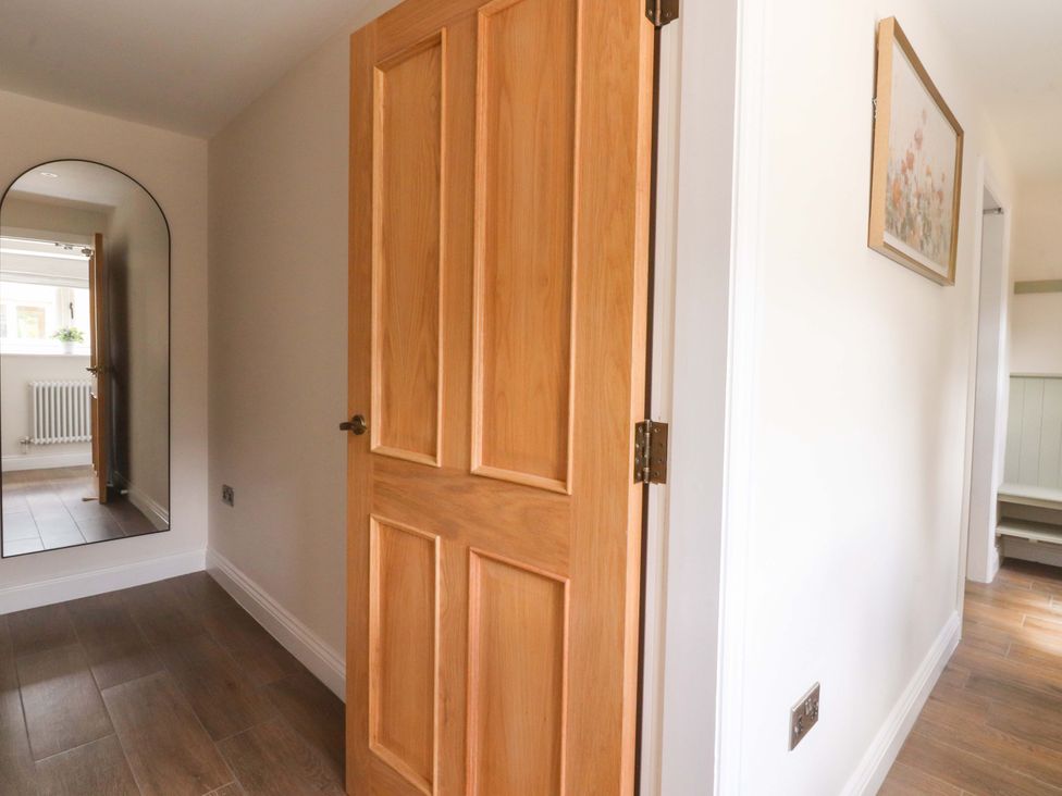 A hallway with a door and a mirror at Heron View