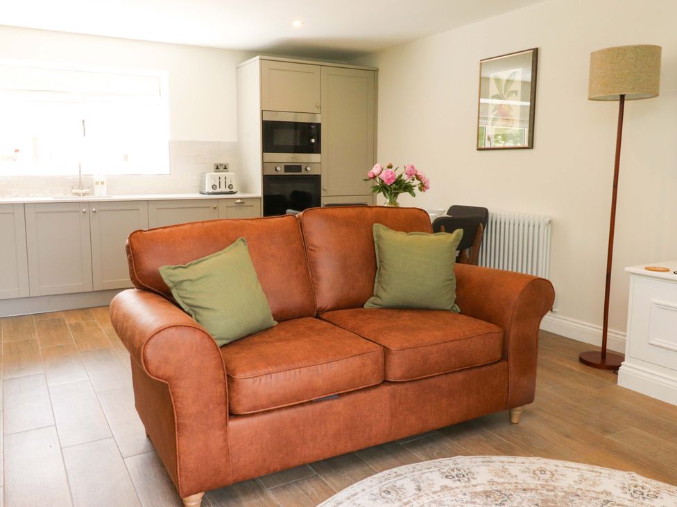 A living room with a sofa and kitchen units at Heron View