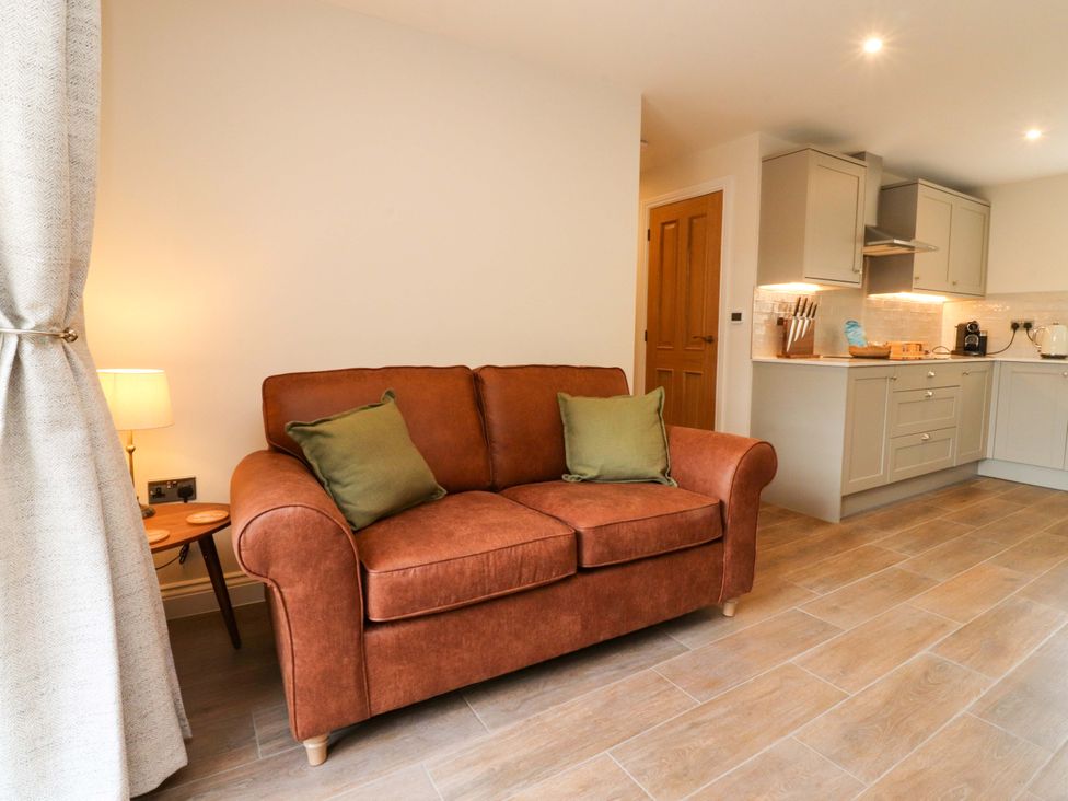 A living room with a sofa and kitchen units at Heron View