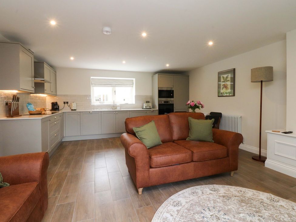 A living room with a sofa and kitchen area at Heron View