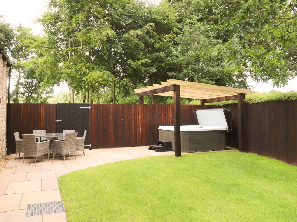 A garden with a dining table and hot tub at Heron View
