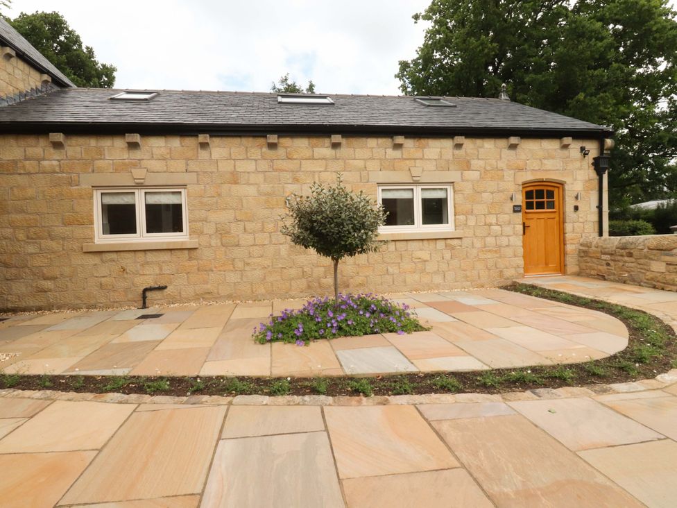 An exterior view of a stone building with a tree and flowers at Heron View