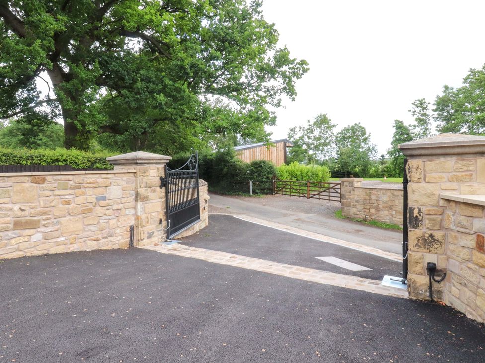 A gate and stone wall entrance with trees at Heron View 