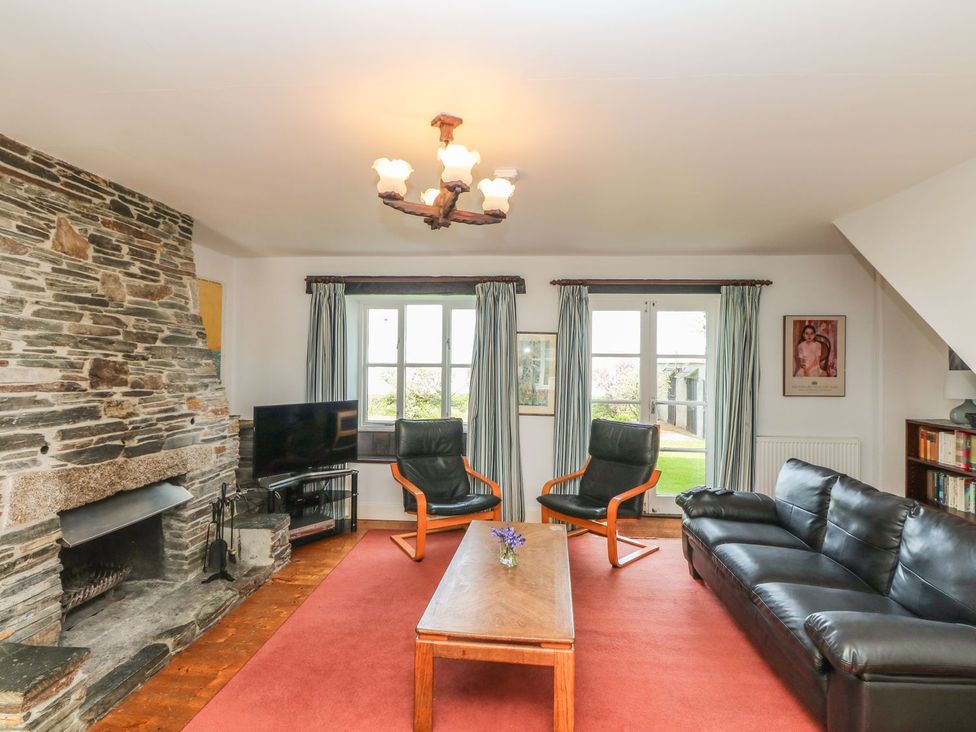A living room with a fireplace and a tv at Tremorla in Boscastle