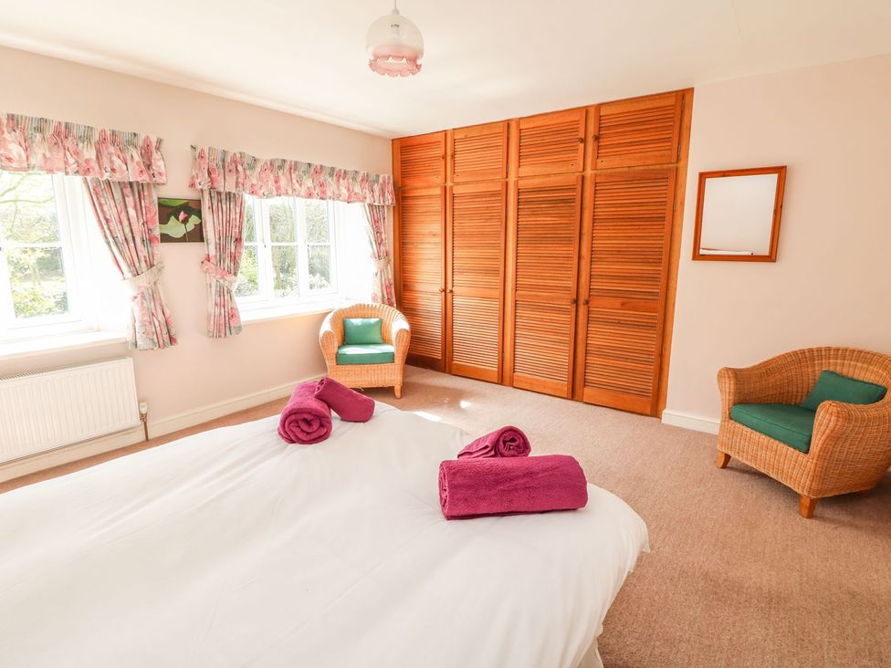 A bedroom with a bed, towels, and wardrobe at Tremorla in Boscastle