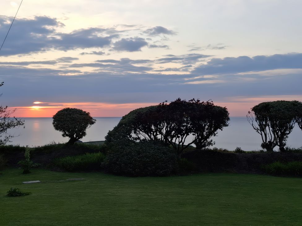A garden with trees and a view of the sunset at Tremorla in Boscastle