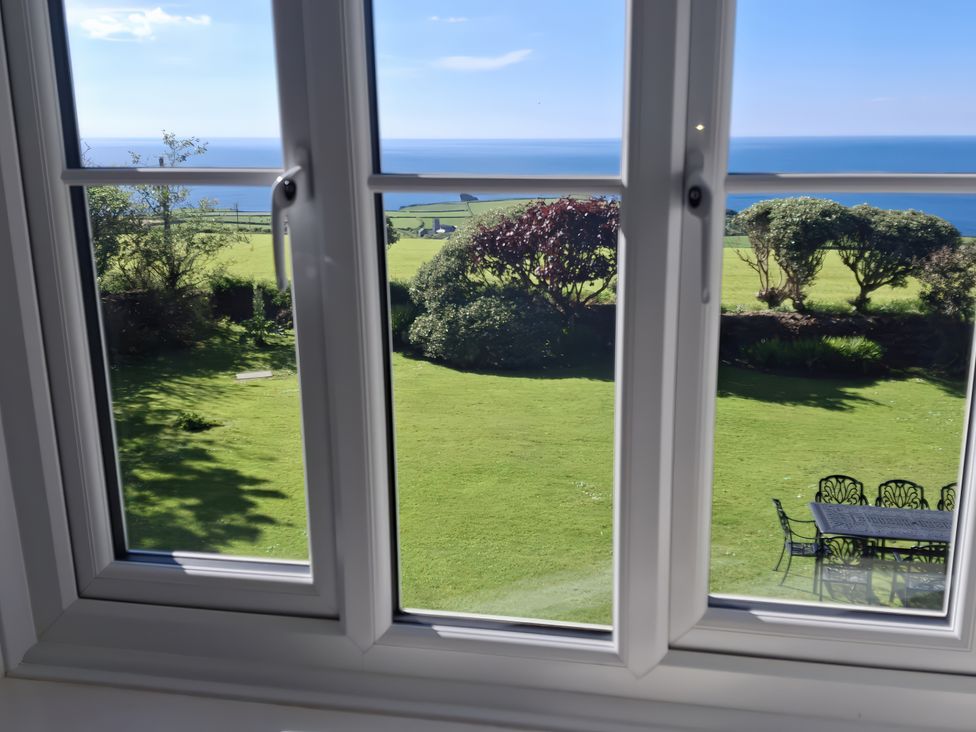 A view through a window showing a garden and sea at Tremorla in Boscastle