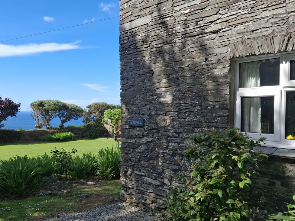 An exterior view of a stone wall with a sign at Tremorla in Boscastle