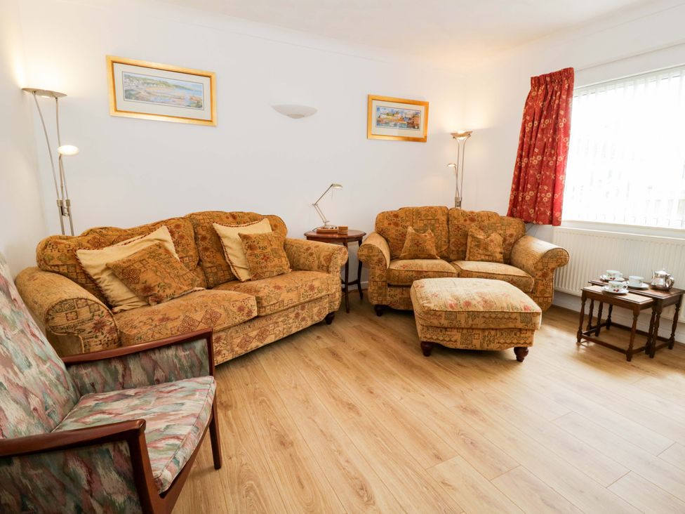A living room with a sofa and armchair at No.1 Vanderhoof Way in Saundersfoot