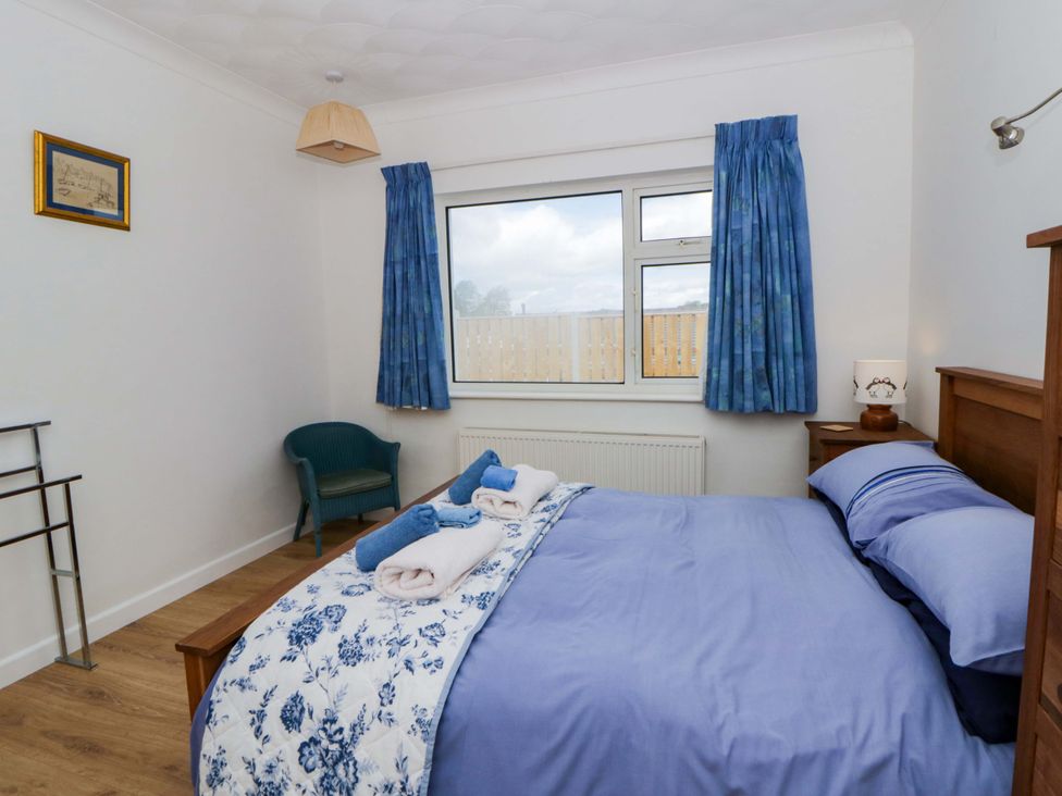 A bedroom with a bed and armchair at No.1 Vanderhoof Way in Saundersfoot