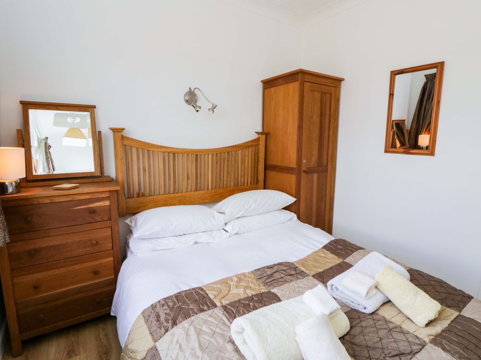 A bedroom with a bed and wooden furniture at No.1 Vanderhoof Way in Saundersfoot