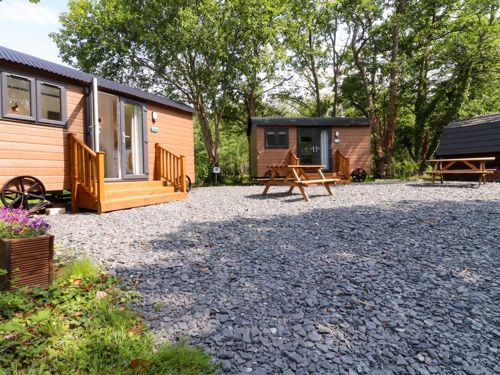 An outdoor area with wooden huts and picnic tables at Shepherds Hut 1