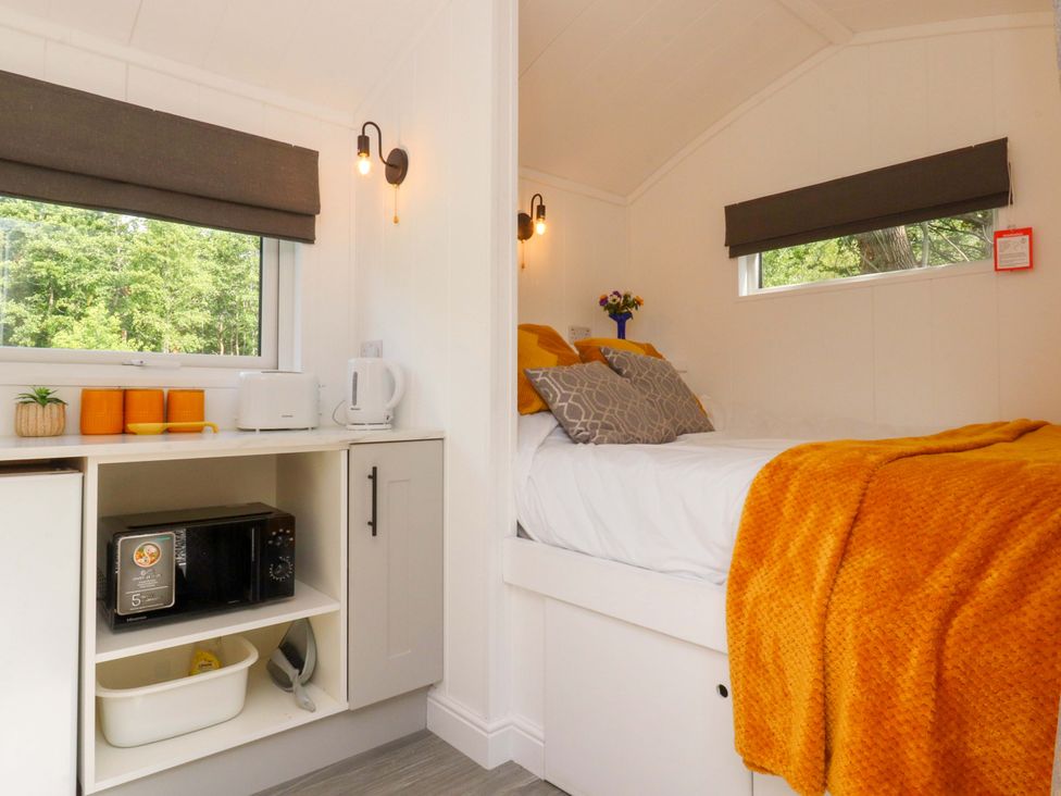 A bedroom with a bed and kitchenette at Shepherds Hut 1