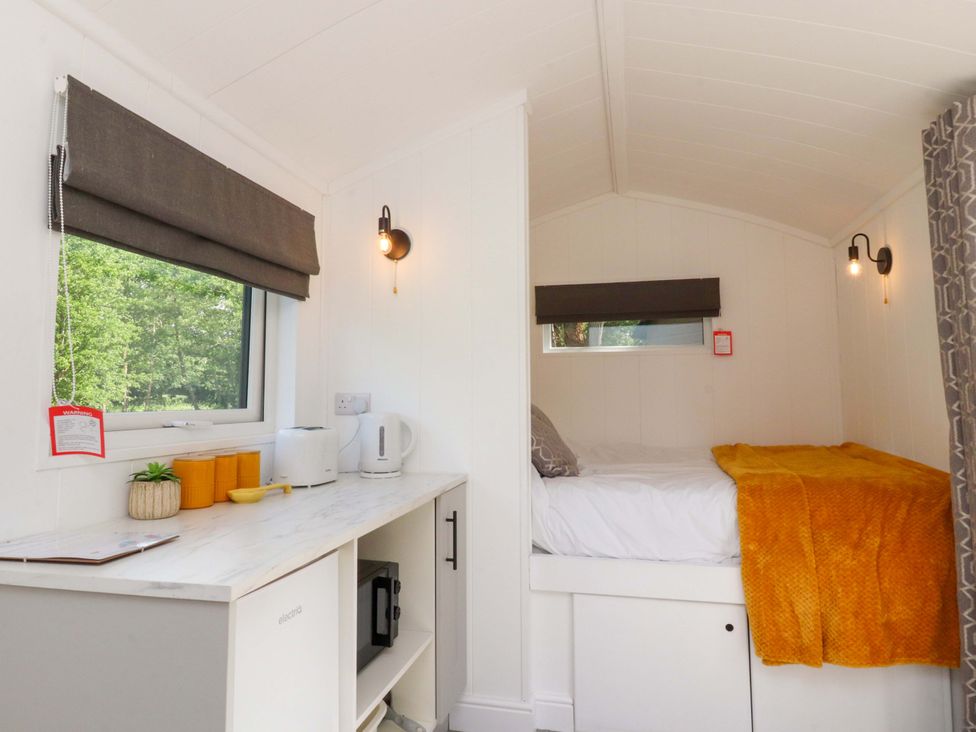 A bedroom with a bed and kitchen appliances at Shepherds Hut 1