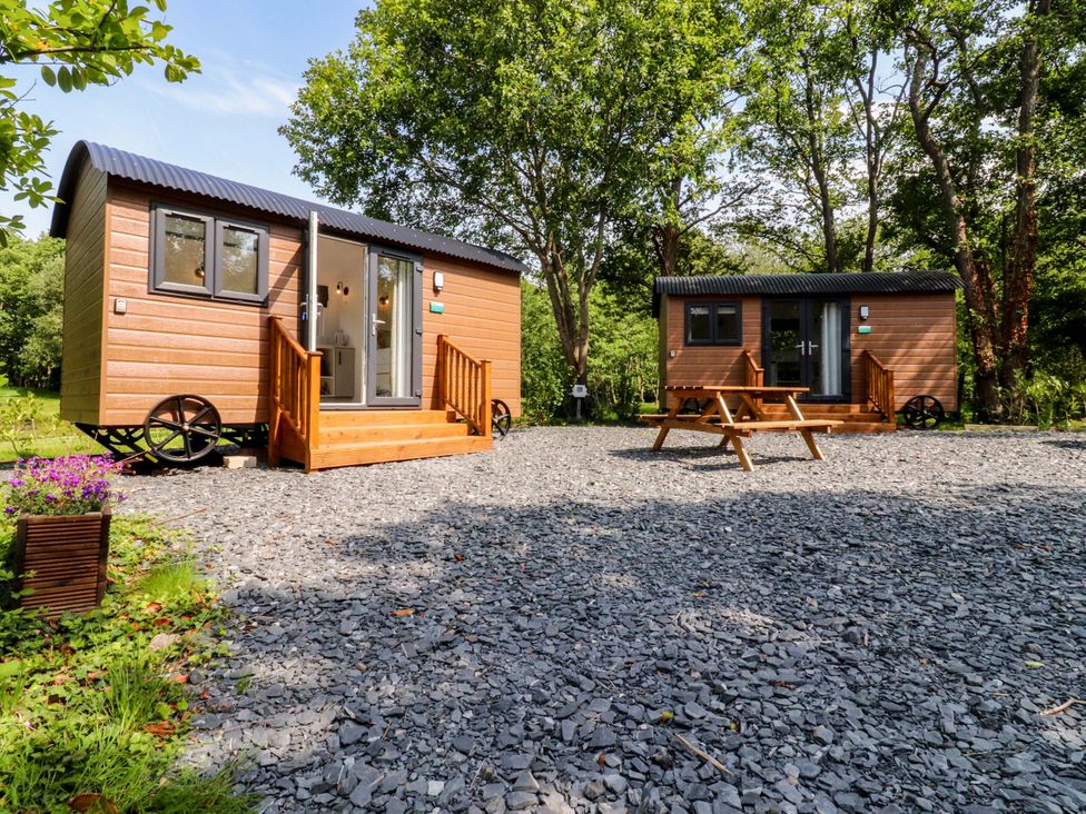 Two wooden huts with decking and outdoor table at Shepherds Hut 1