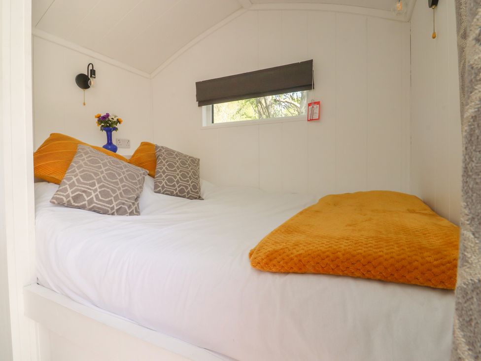 A bedroom with a bed and flowers on a table at Butterfly Hut 1 in Forton near Garstang