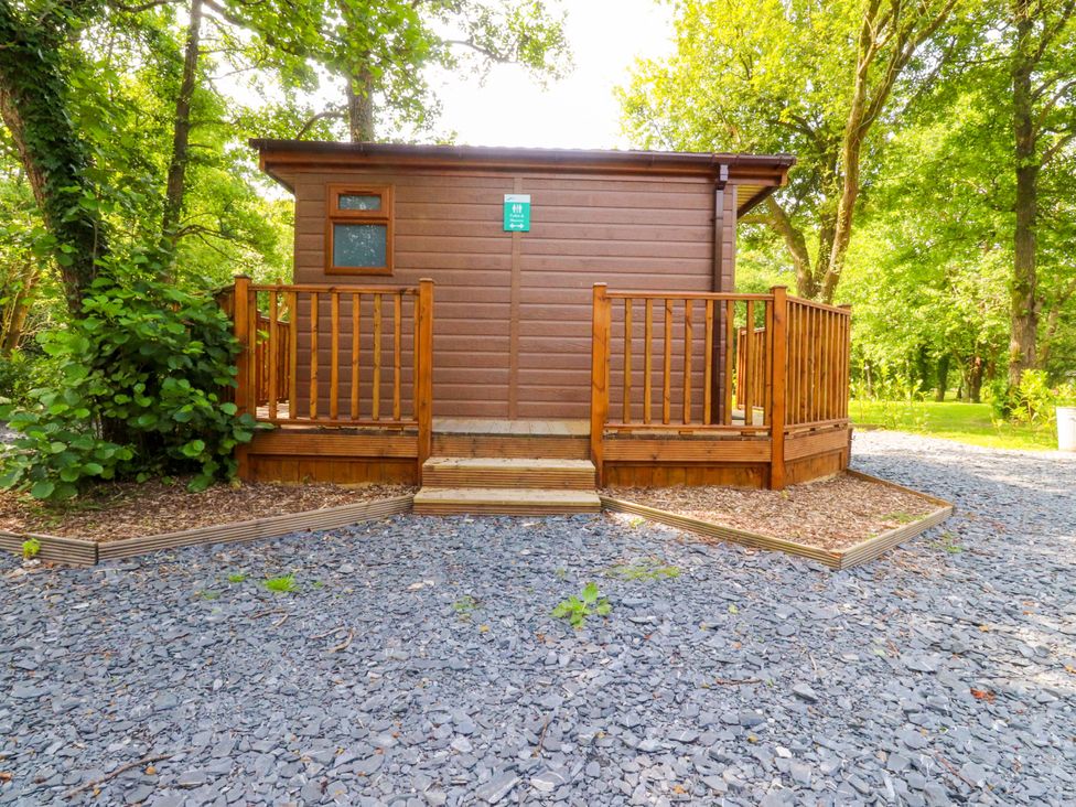 A cabin with a deck surrounded by trees at Shepherds Hut 2