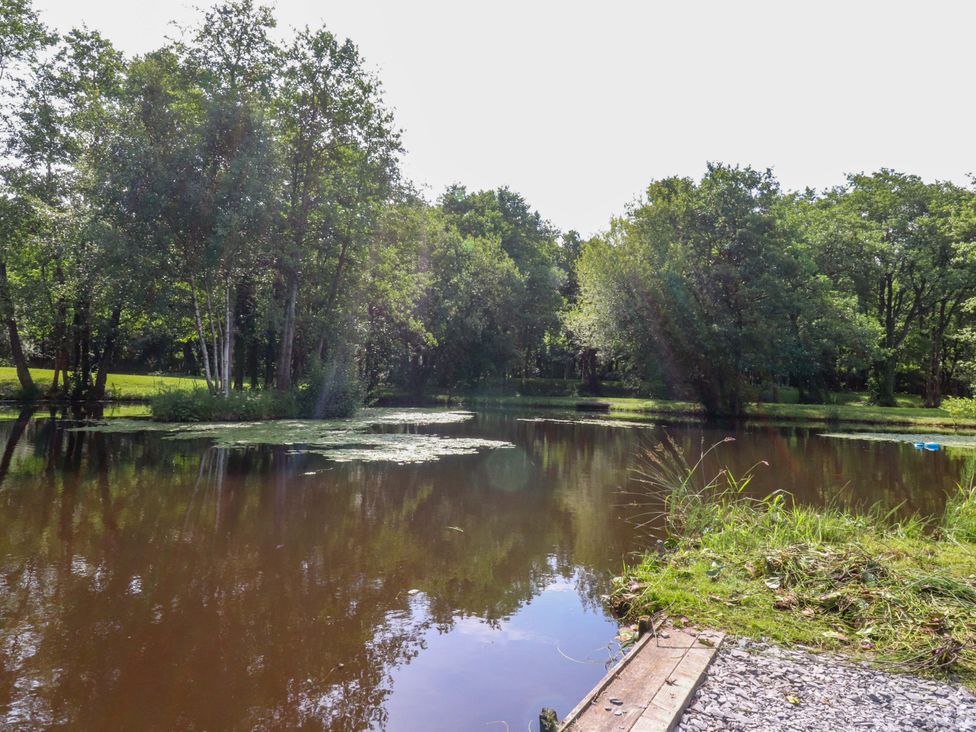 A pond surrounded by trees and grass at Shepherds Hut 2