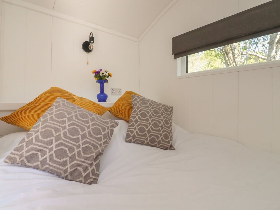 A bedroom with pillows and flowers at Butterfly Hut 2 Forton near Garstang