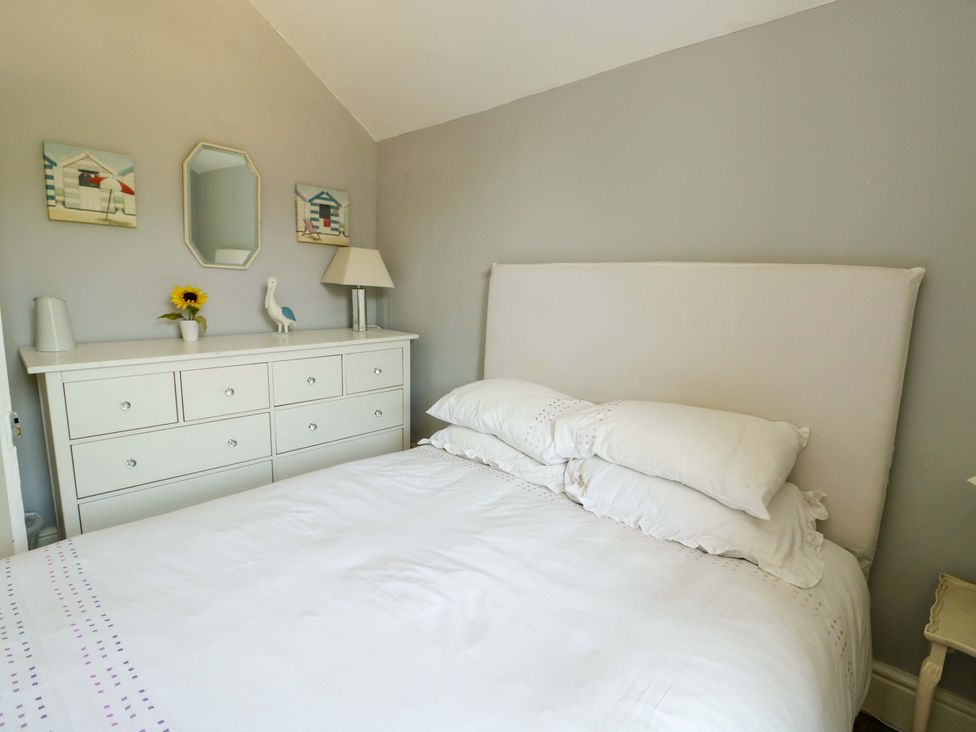 A bedroom with a bed and dresser at Trwst Y Don in Rhosneigr