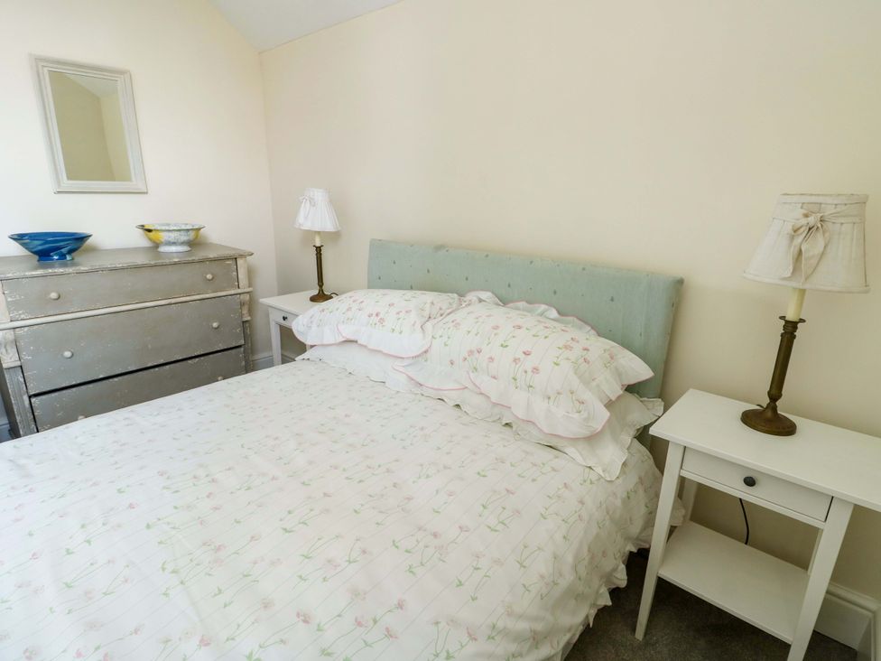 A bedroom with a bed and dresser at Trwst Y Don in Rhosneigr