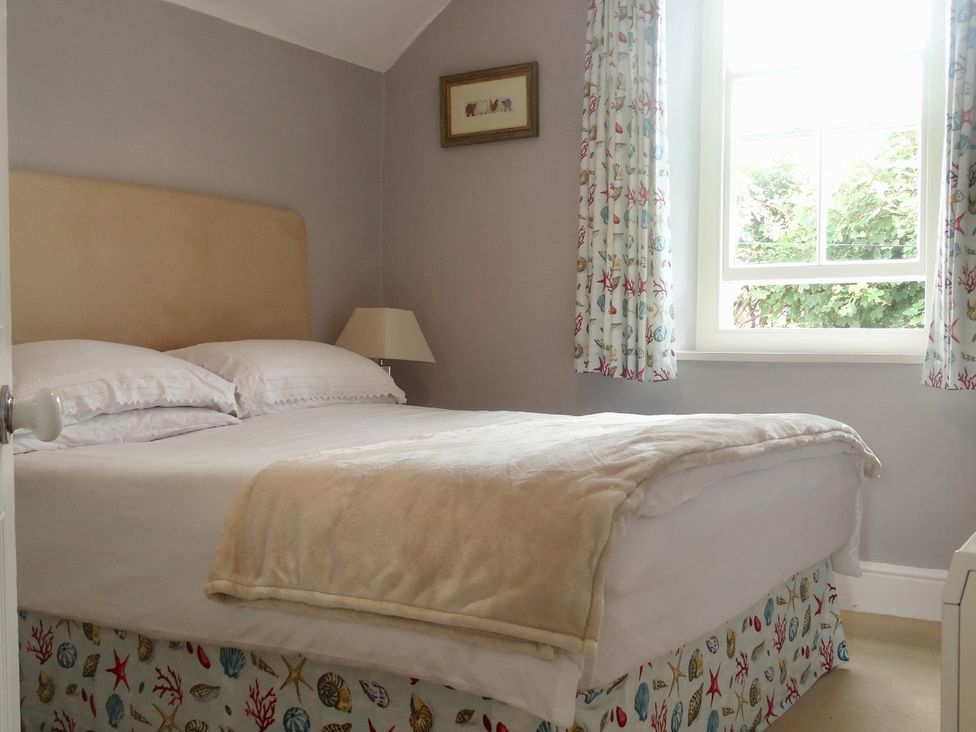 A bedroom with a bed and a window at Trwst Y Don in Rhosneigr