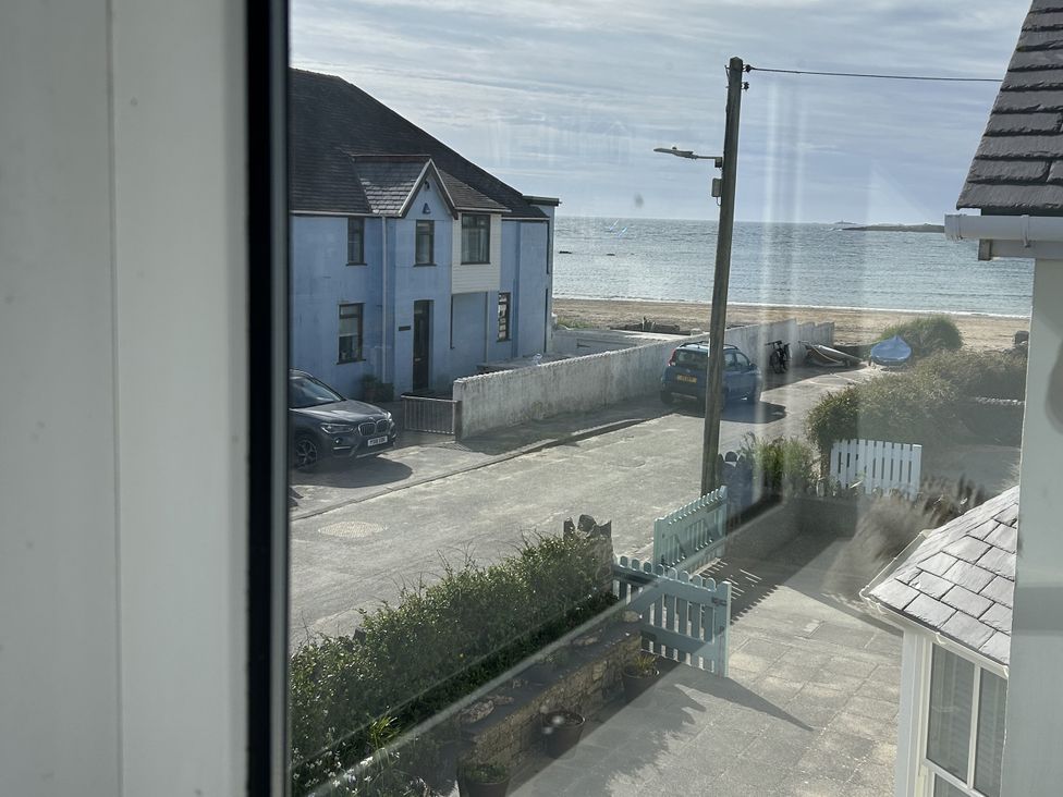 A view of a building and ocean from a window at Trwst Y Don Rhosneigr