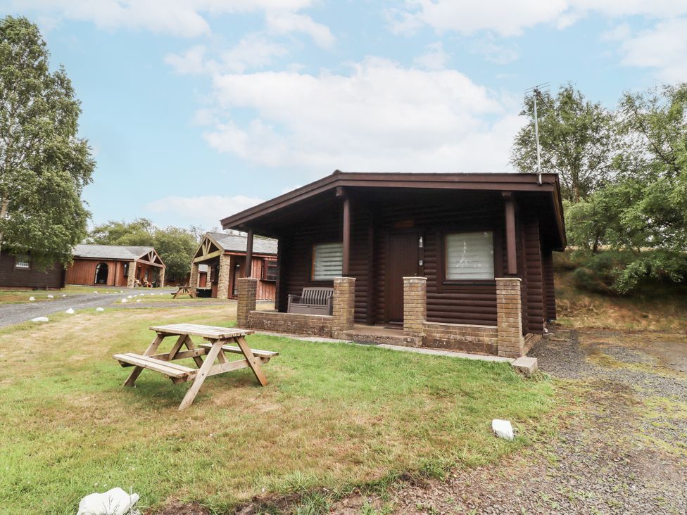 A log cabin with a picnic table in front at Farnes Lodge Longframlington