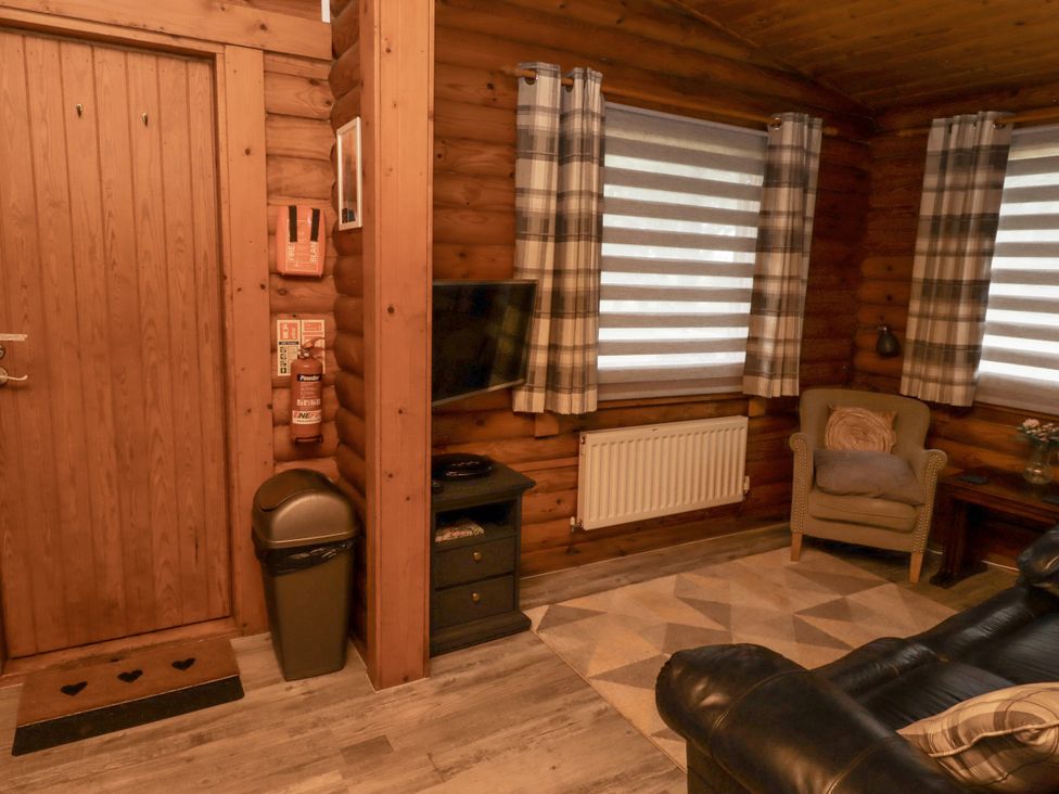 A living room with a television and an armchair at Farnes Lodge in Longframlington