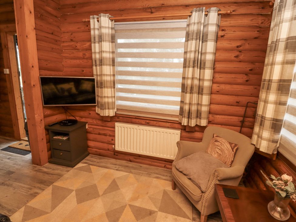 A living room with a television and an armchair at Farnes Lodge in Longframlington