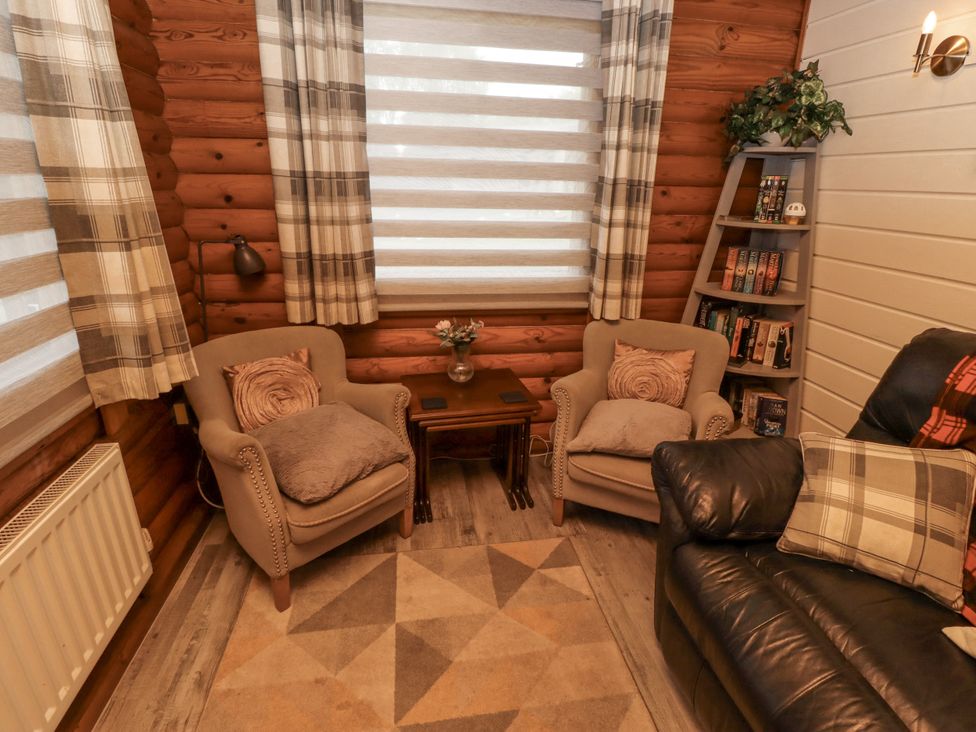 A snug with armchairs and a table at Farnes Lodge in Longframlington