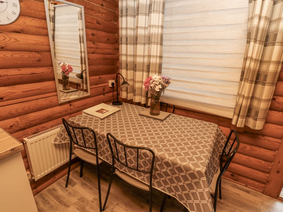 A dining room with a table and chairs at Farnes Lodge in Longframlington