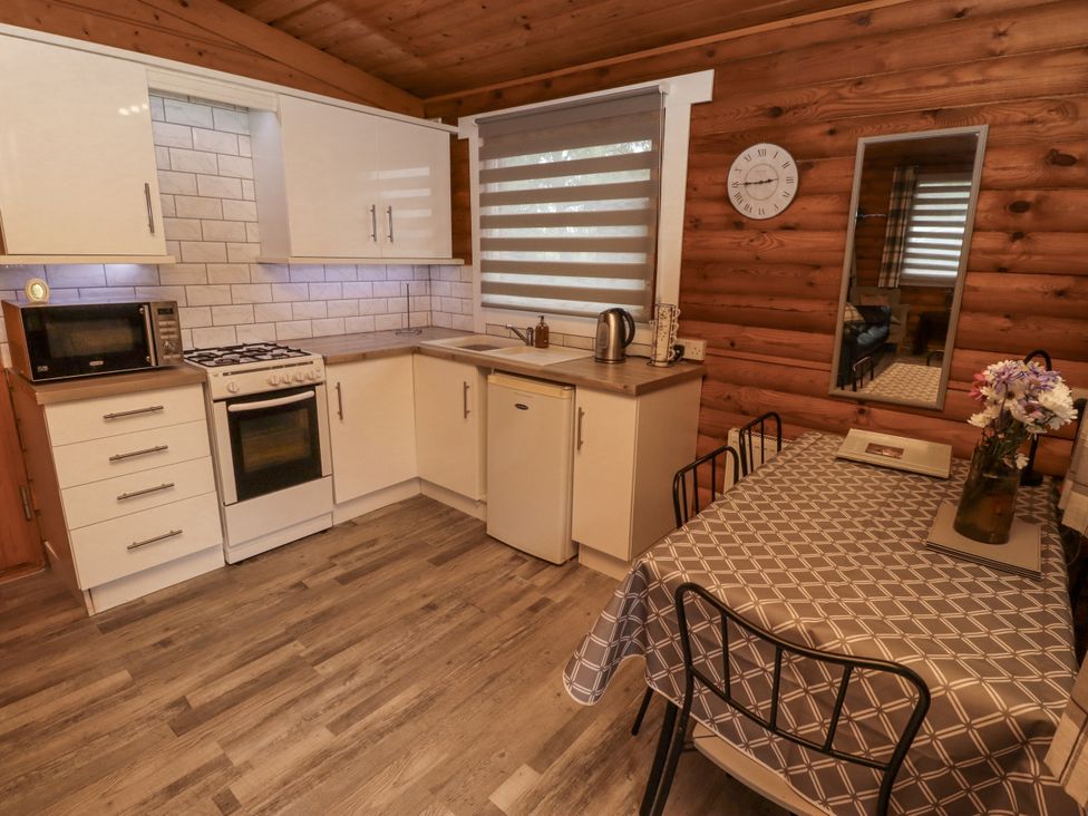 A kitchen with appliances and a dining table at Farnes Lodge in Longframlington