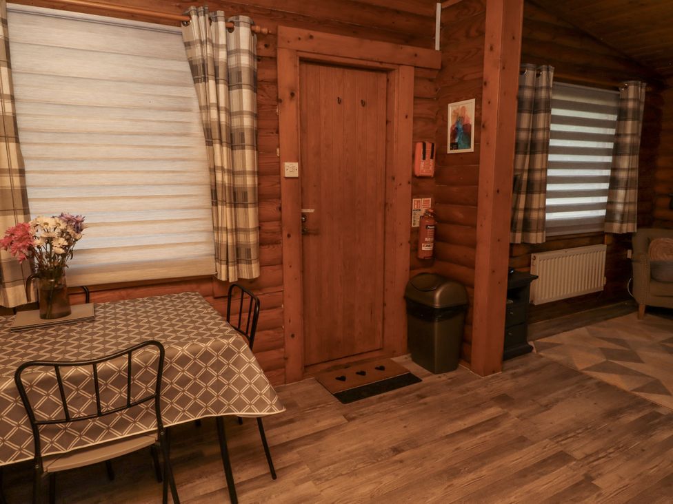 A dining room with a table and chairs at Farnes Lodge in Longframlington