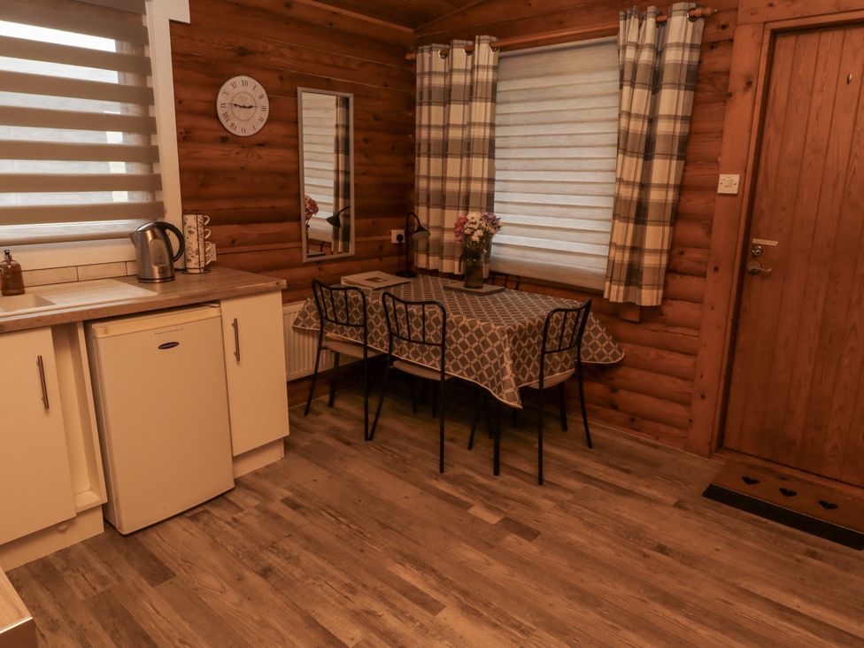 A dining room with a table and chairs at Farnes Lodge in Longframlington