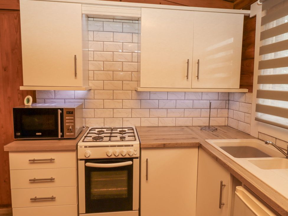 A kitchen with a microwave stove and sink at Farnes Lodge in Longframlington
