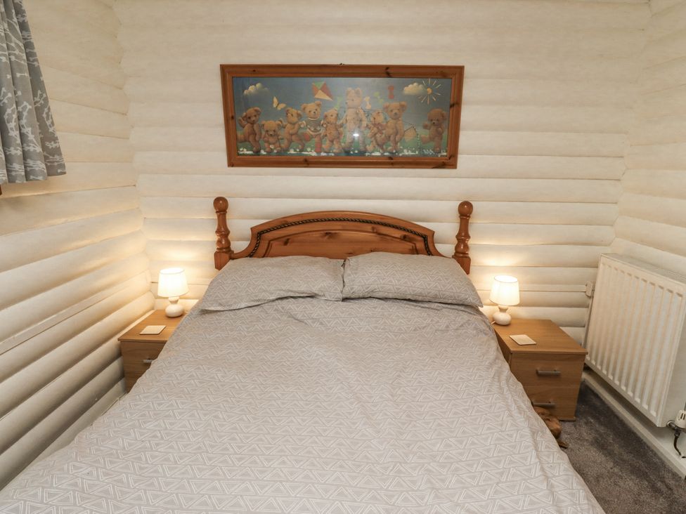A bedroom with a bed, nightstand, lamp, and radiator at Farnes Lodge in Longframlington