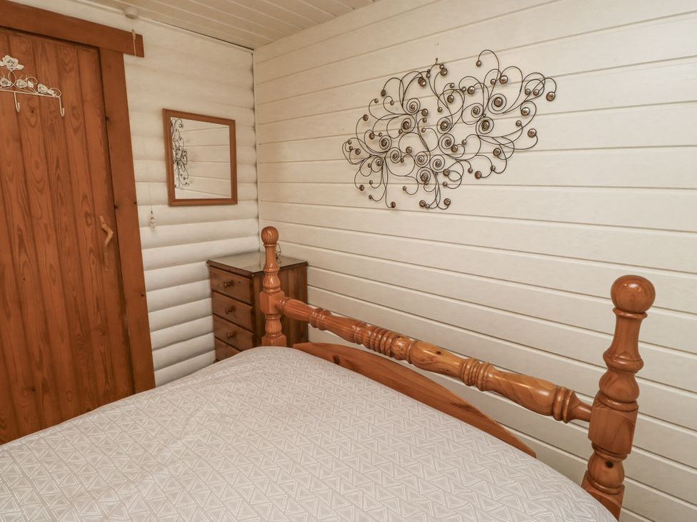 A bedroom with a bed and wooden furniture at Farnes Lodge Longframlington