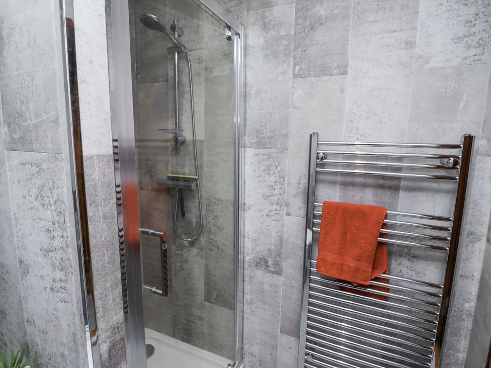 A shower enclosure with glass doors in a bathroom at Farnes Lodge Longframlington