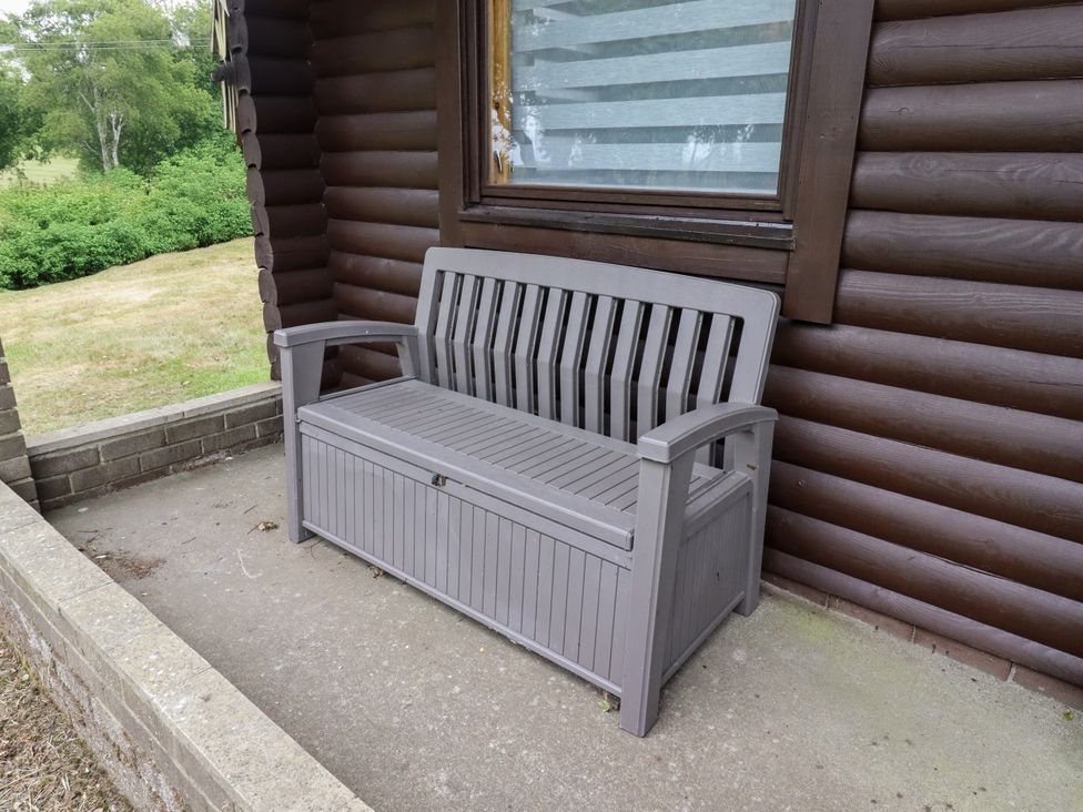 A bench in front of a log cabin at Farnes Lodge Longframlington