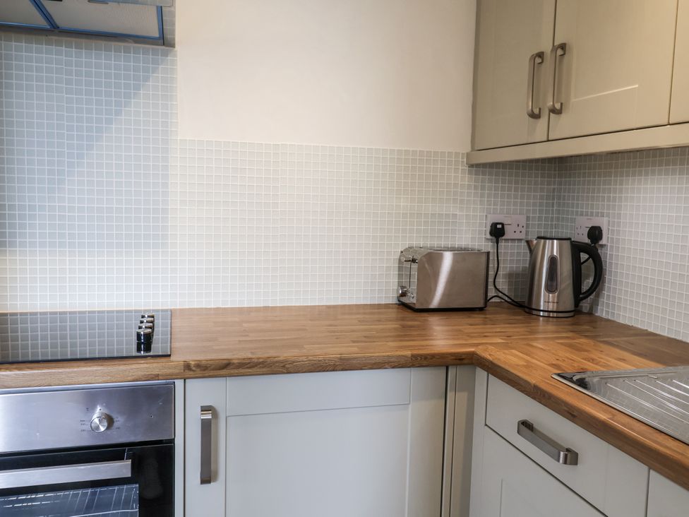 A kitchen with an oven, kettle, toaster, and sink at The Annex next to St Johns Southwold