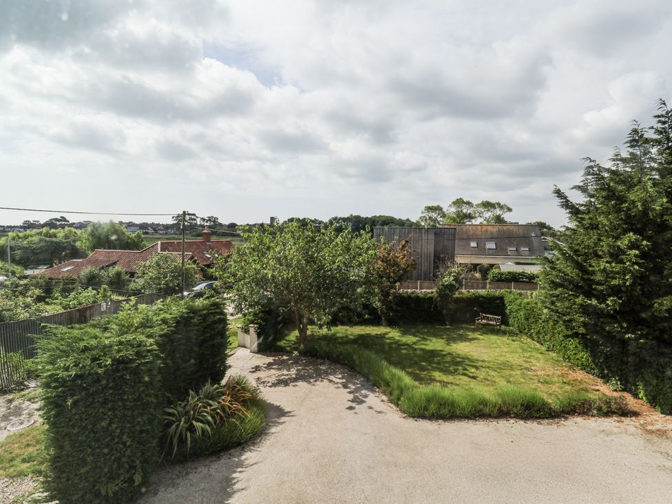 A garden with trees and a house in the background at The Annex next to St Johns Southwold