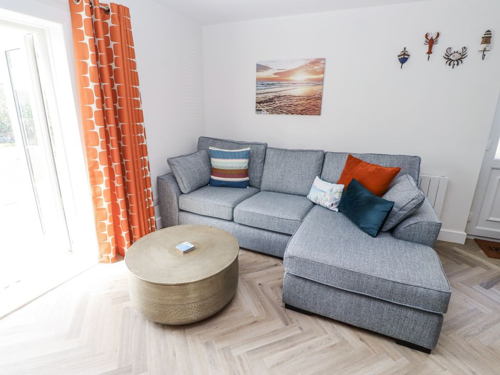 A living room with a sofa and a coffee table at Seahorse Cottage in Chathill