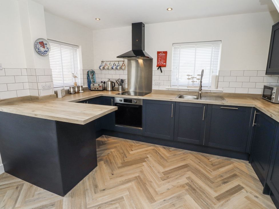 A kitchen with a sink, oven, and kettle at Seahorse Cottage in Chathill